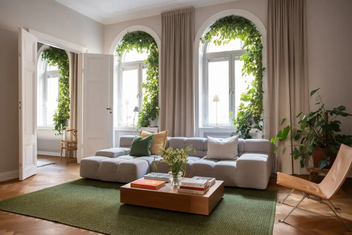 Arched Windows and Design Classics in a 19th Century Apartment 1 living room with plant-covered arched windows