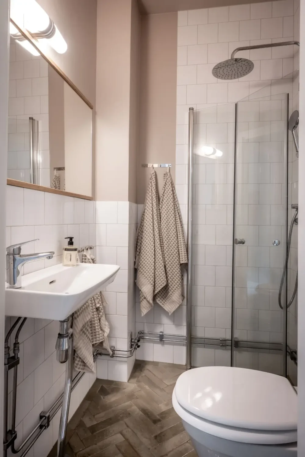 An Earthy Color Palette and Exposed Brick in a 1940s Apartment 28 small-bathroom-sand-colored-walls-herringbone-tile-floor-nordroom