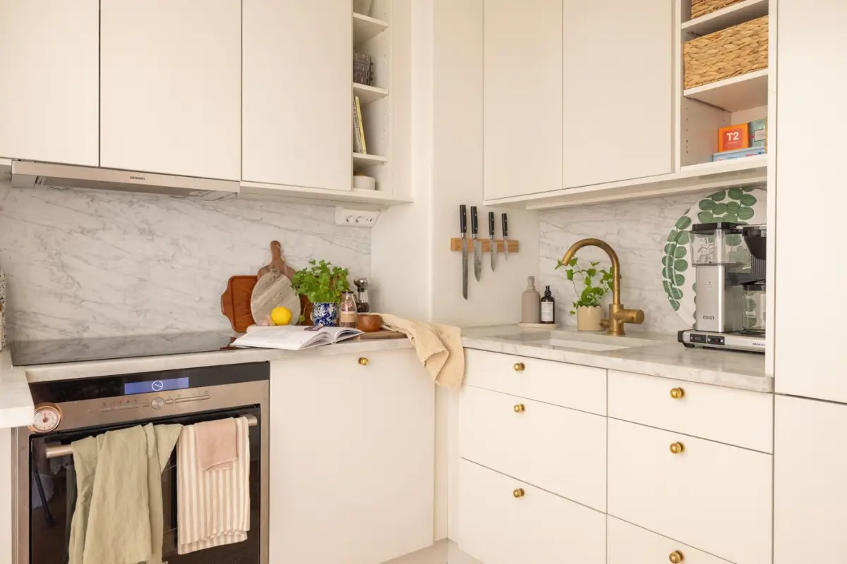 A Small Beige Stockholm Apartment with Plenty of Storage 11 small white kitchen brass fittings marble countertop backsplash