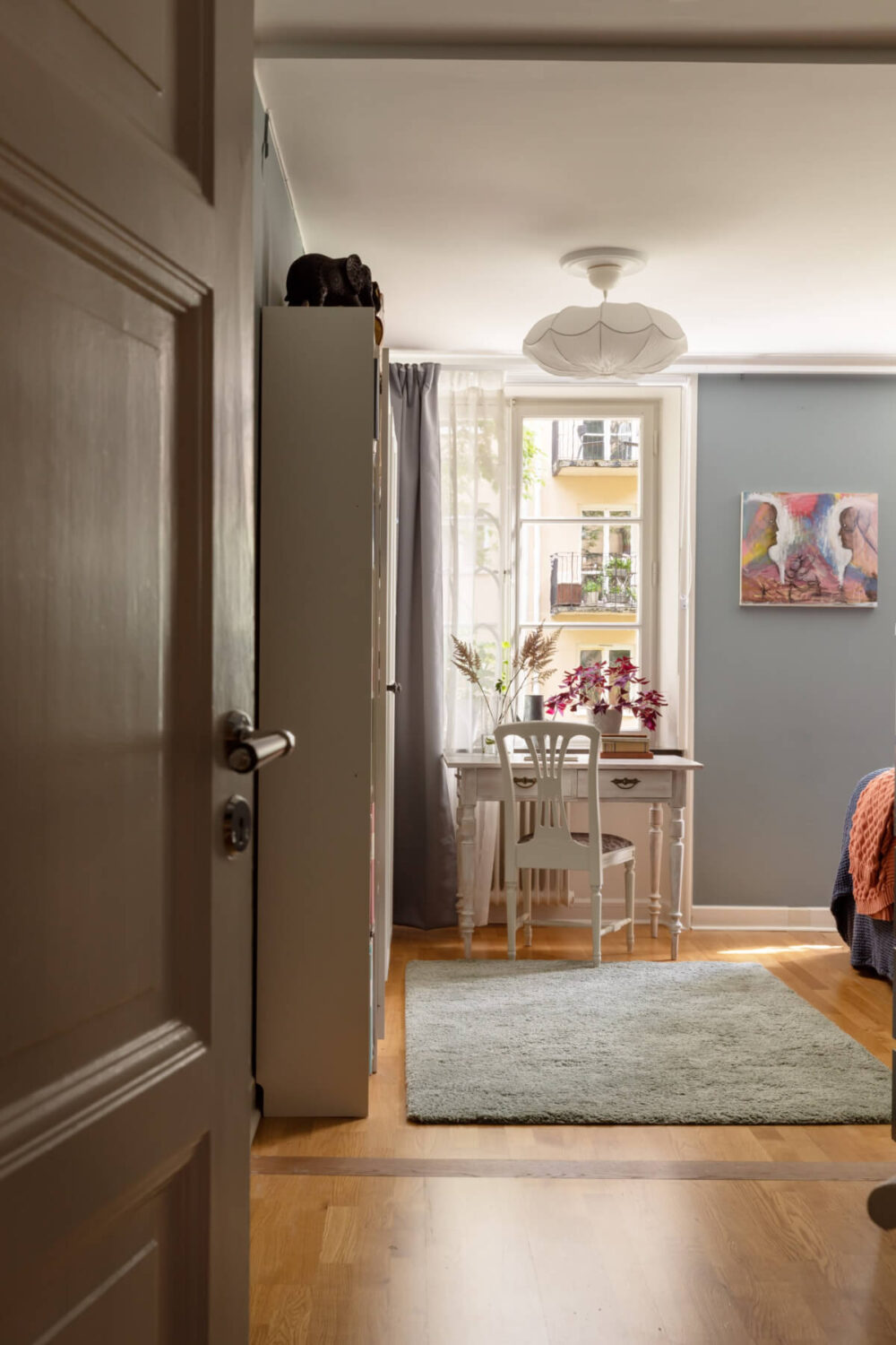 A 1930s Stockholm Apartment With Views of a Lush Garden 13 view into blue bedroom with desk