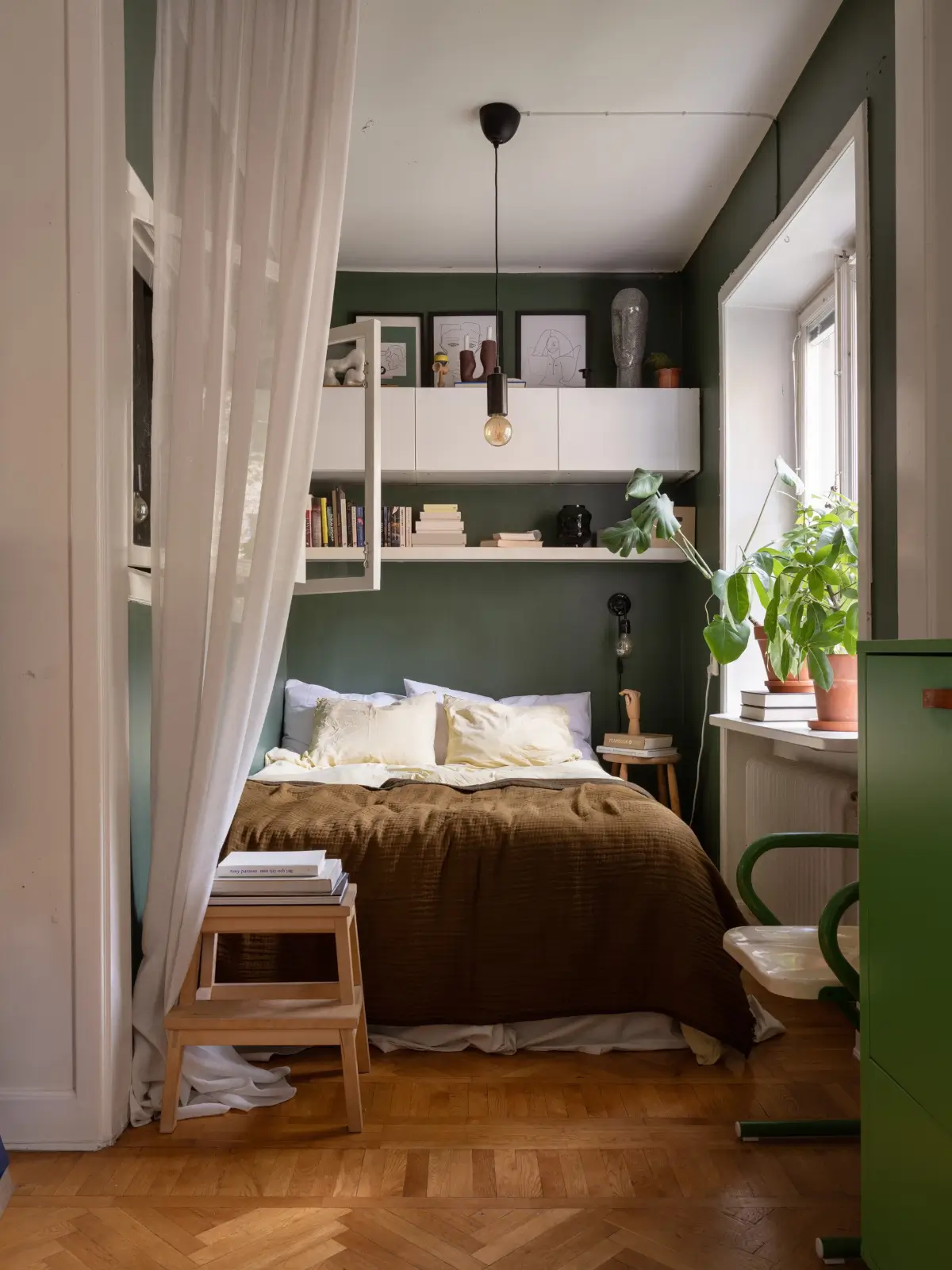 dark green bed nook with shelves and high cabinets