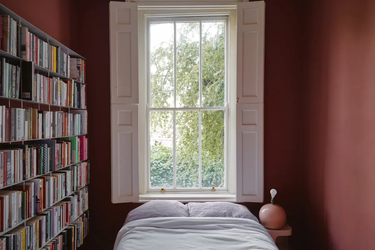 Restored Features in a Charming Georgian Apartment in London 16 dark red color-drenched bedroom bookshelves bed under window nordroom