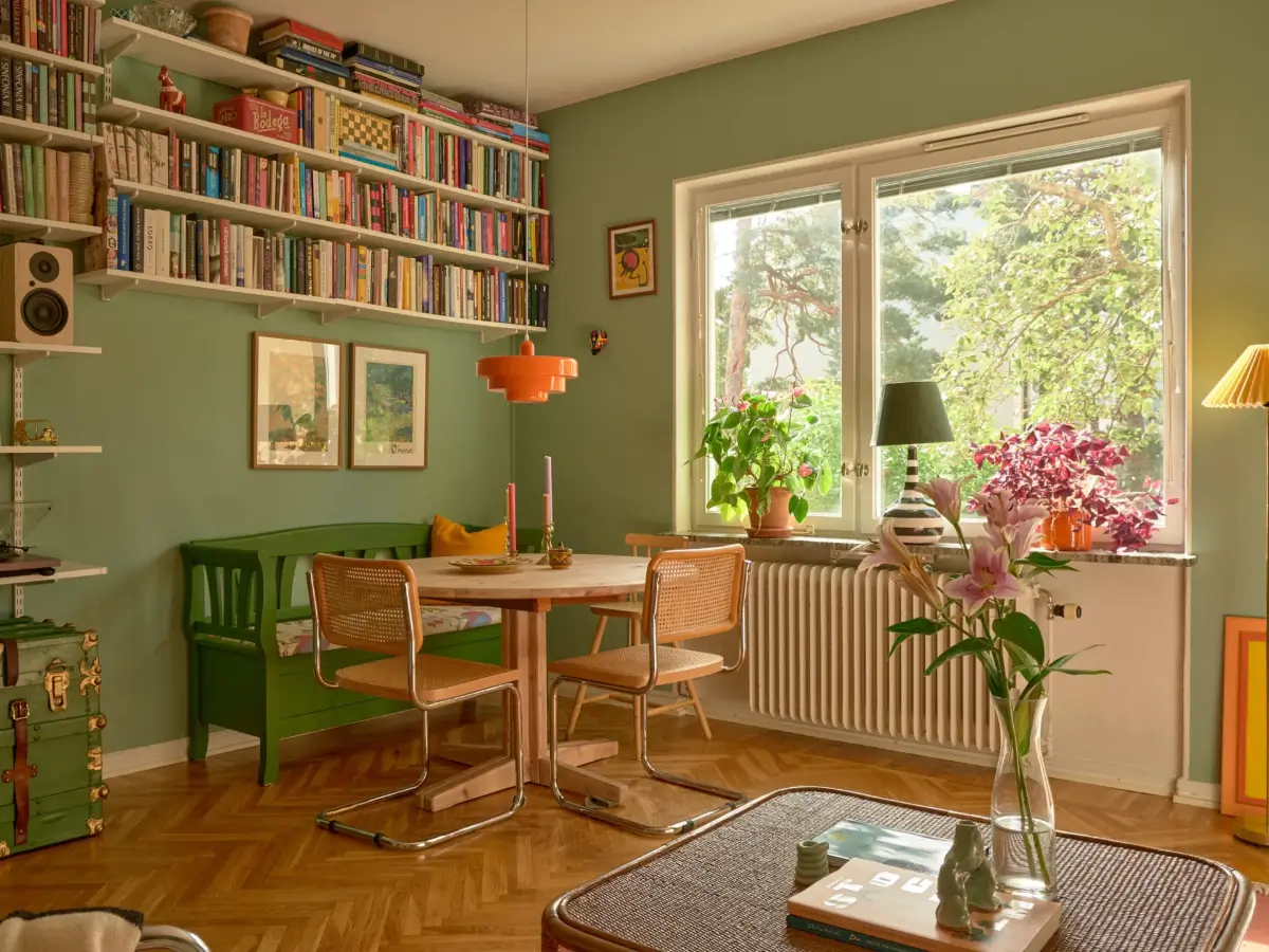 A Colorful and Cozy Midcentury Apartment in Stockholm 1 green living room herringbone floor wooden table bookshelves nordroom