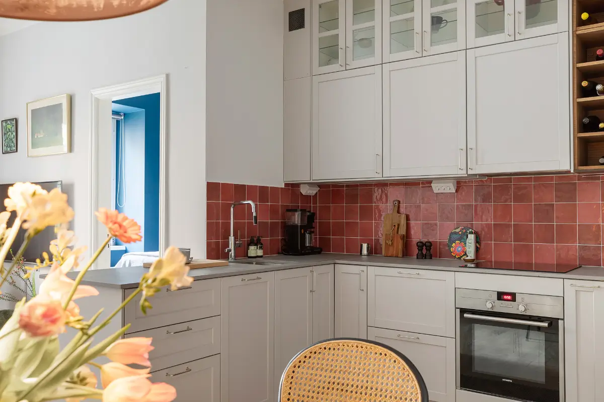 Red and Blue Color Accents in an Open-Plan Stockholm Apartment 12 light gray kitchen cabinets red backsplash tiles