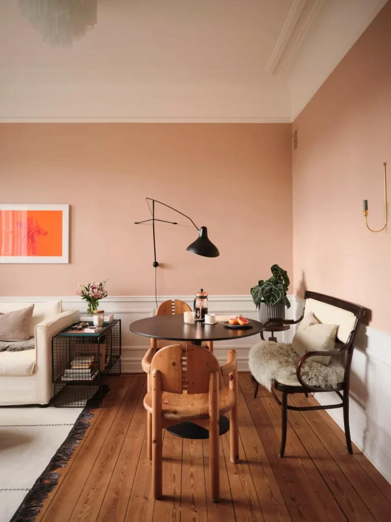 living room warm pink walls wooden floorboards black round dining table nordroom