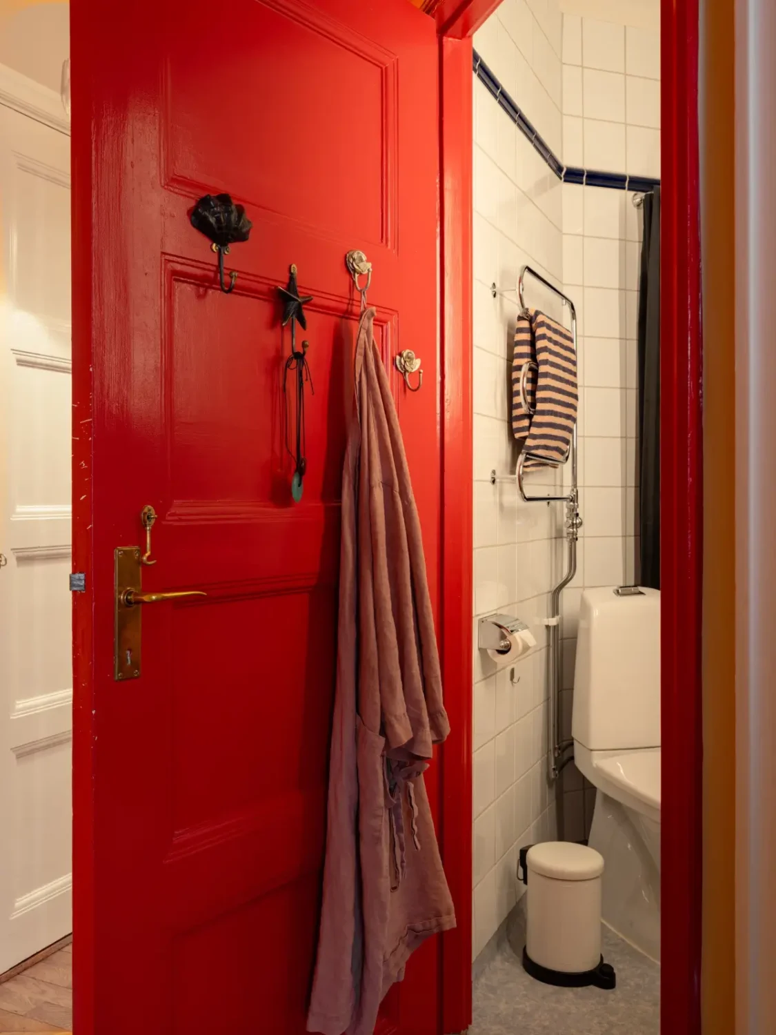 Warm Beige Walls and Practical Niches in a 1920s Studio Apartment 14 red painted door