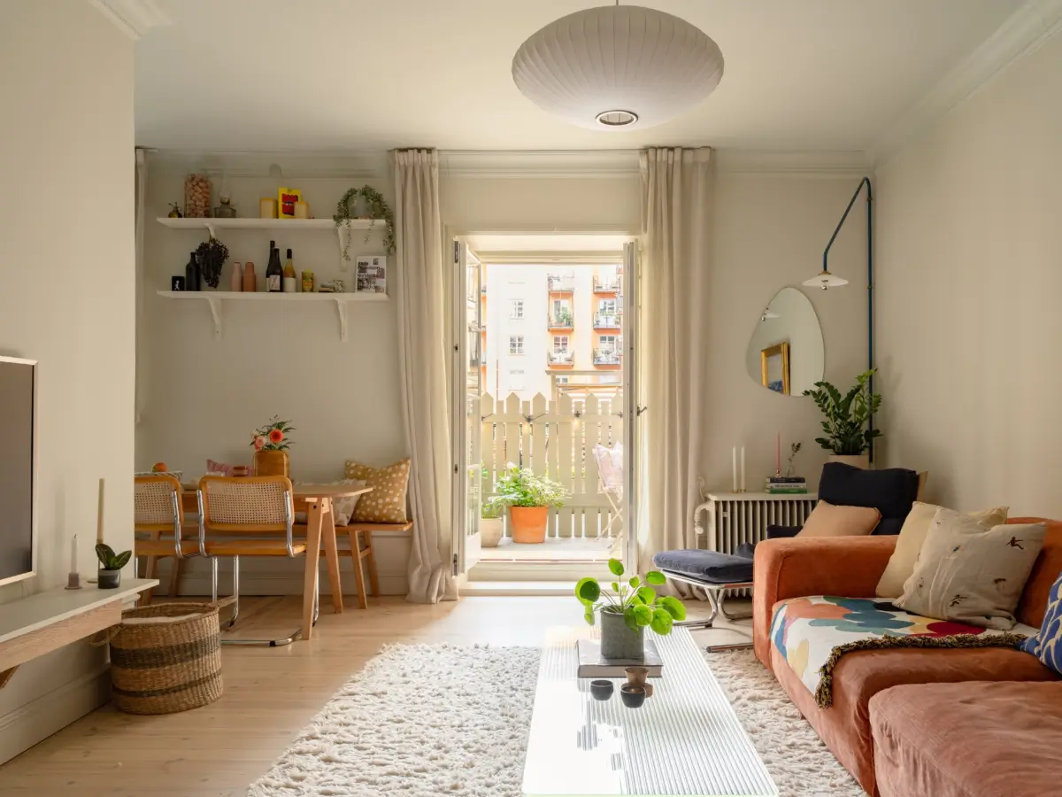 A Light Color Palette and a Charming Private Patio in a Stockholm Apartment 1 scandi living room orange sofa terrace doors