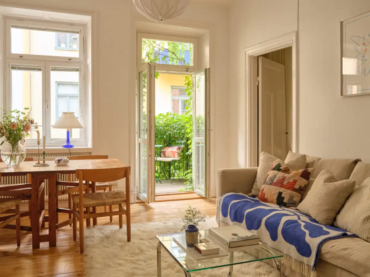 A Lush Balcony and Charming Rooms in a Late 19th Century Apartment 2 scandi living room wooden dining table glass balcony doors
