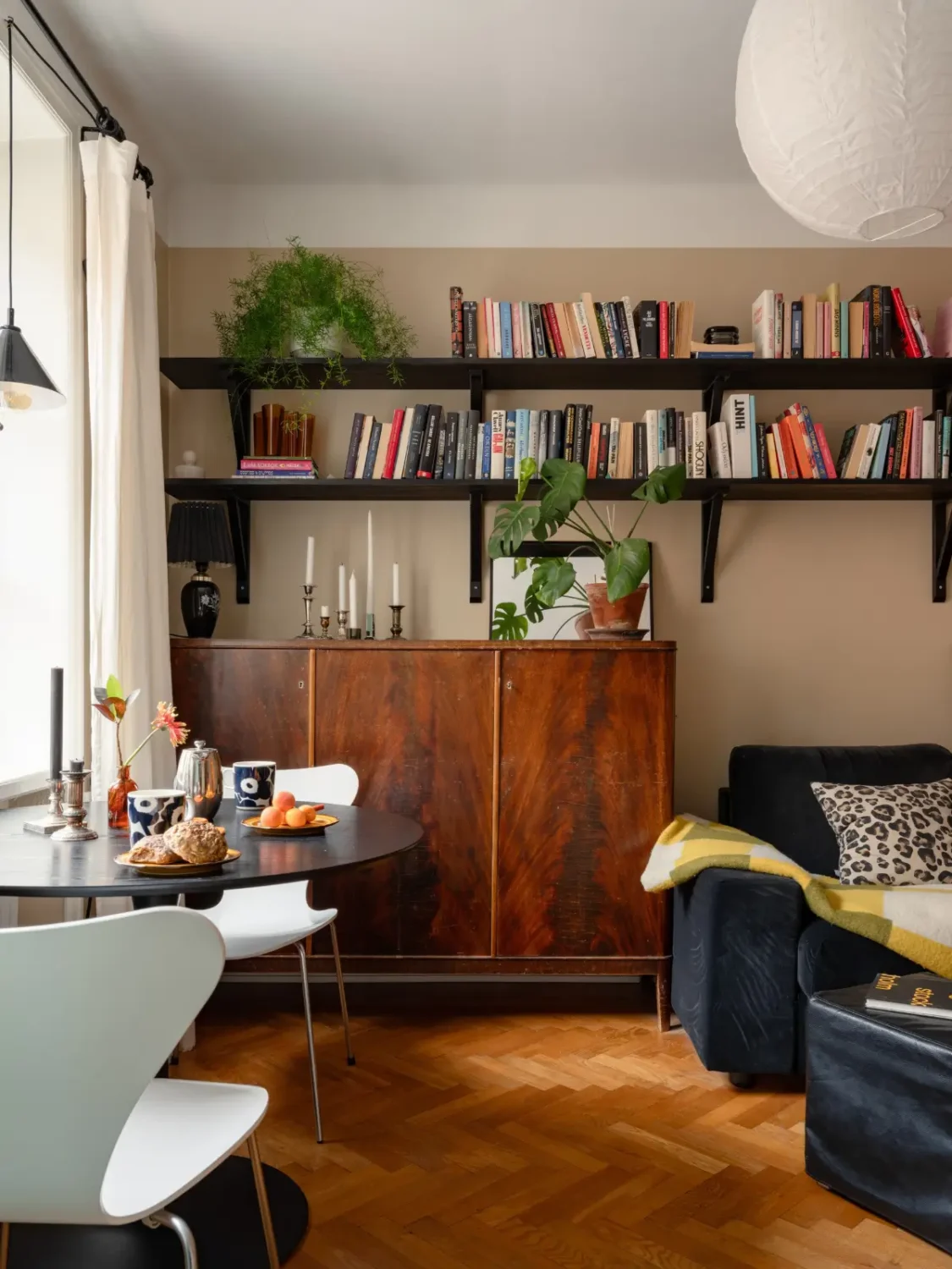 Warm Beige Walls and Practical Niches in a 1920s Studio Apartment 8 studio high bookshelves parquet floor dark beige walls