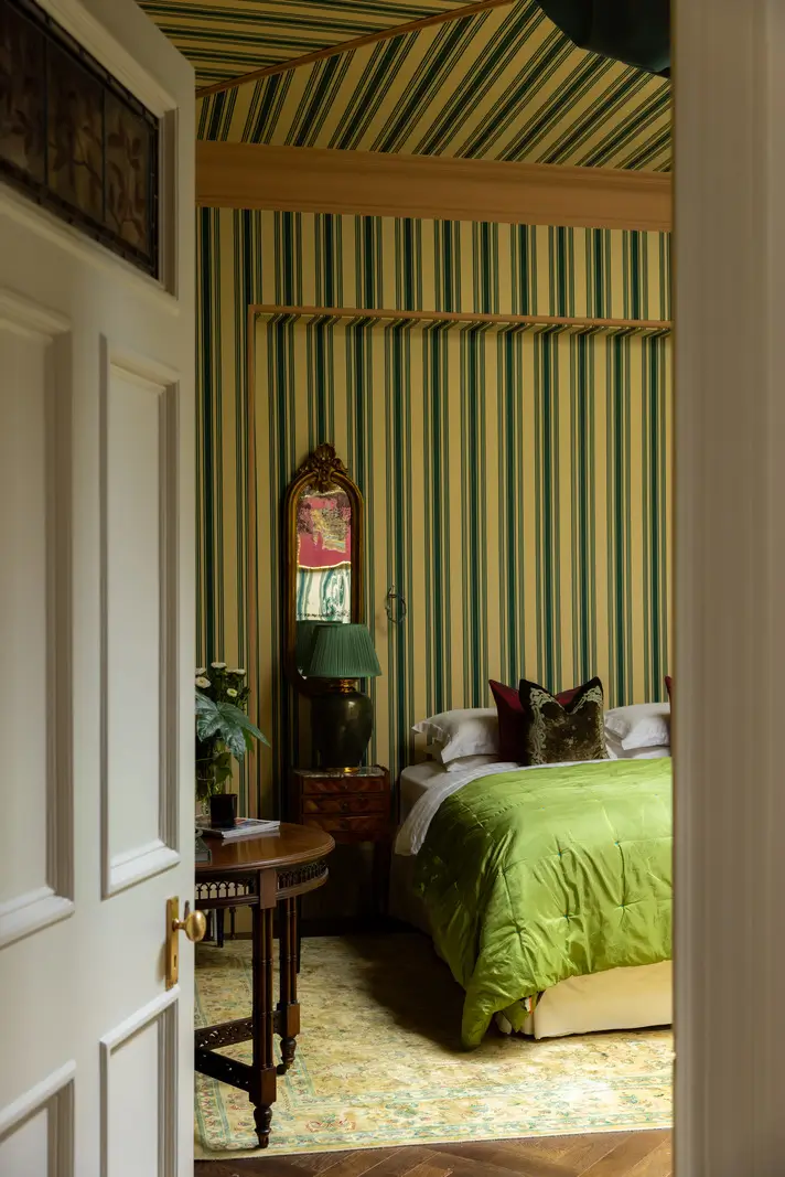 A Mixture of Patterns, Colors, and Materials in a Stunning London Apartment 19 view into bedroom striped wallpaper