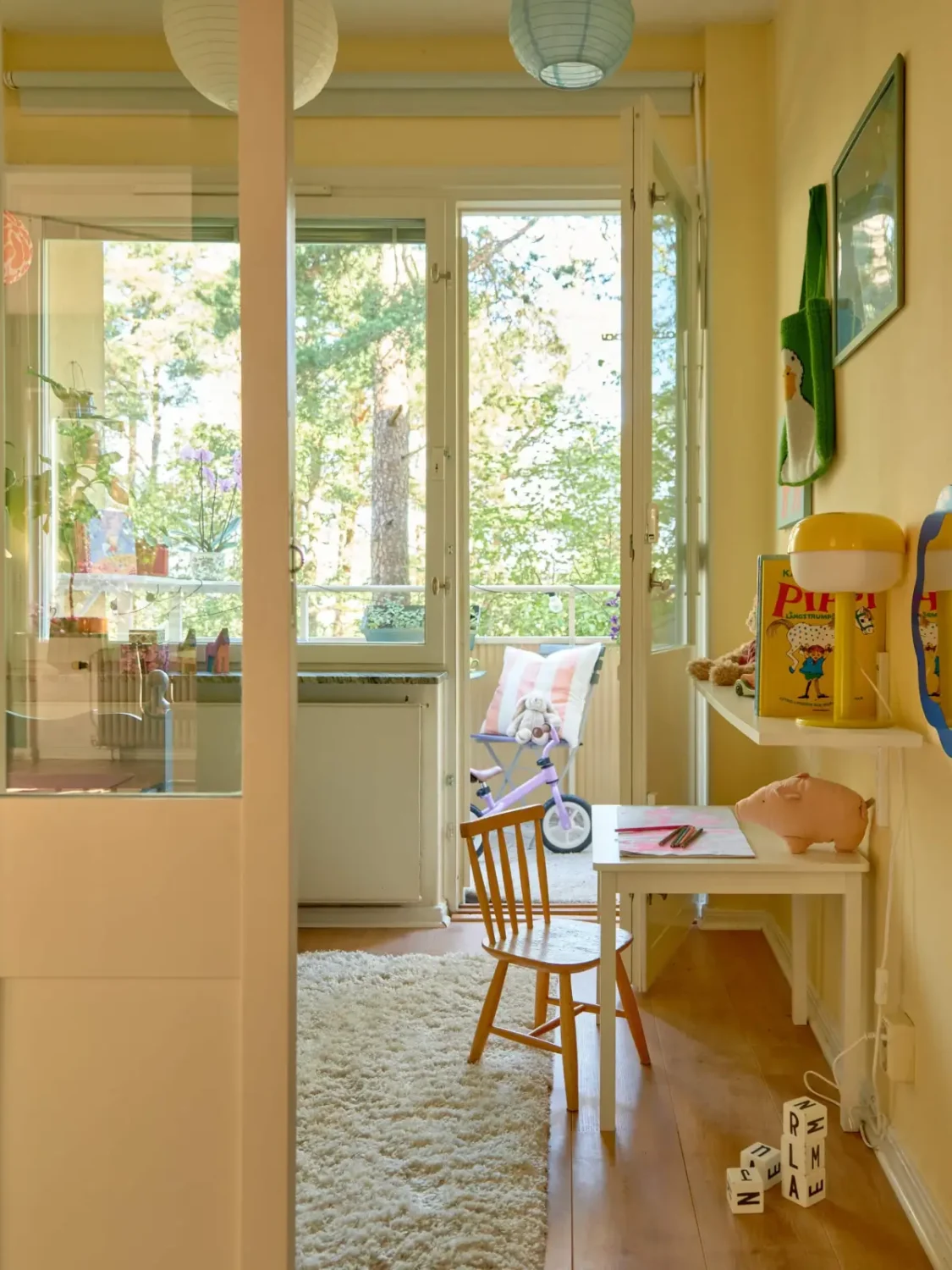 A Colorful and Cozy Midcentury Apartment in Stockholm 19 view into light yellow kids bedroom with balcony