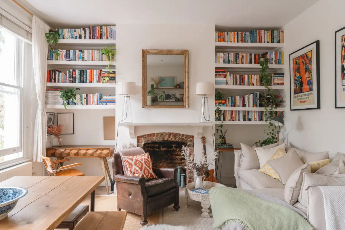 A Bright and Cozy One-Bedroom Apartment in London 1 white living room brick fireplace built-in bookshelves leather chair