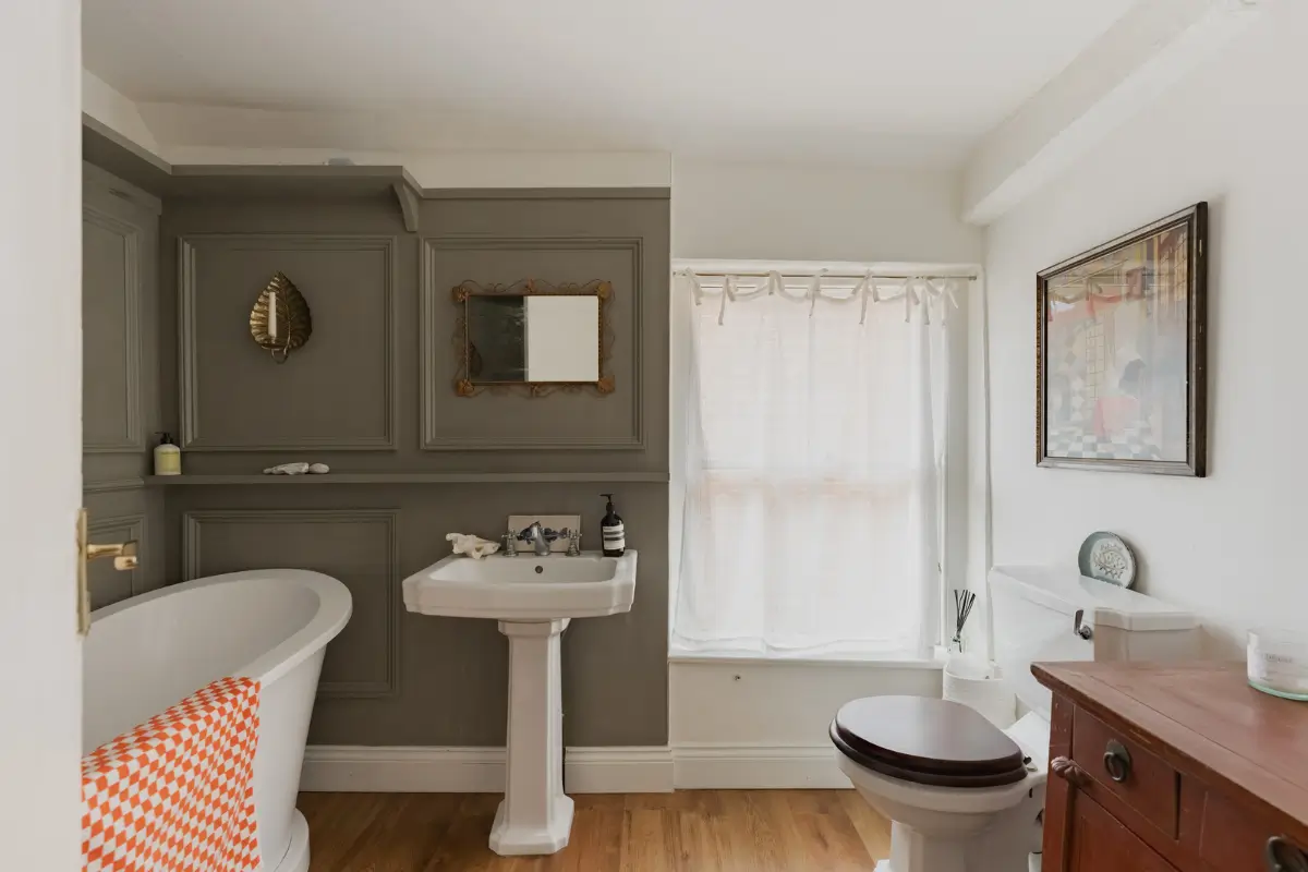 A Charming English Cottage with a Sage-Green Kitchen 20 cottage bathroom gray paneling freestanding bath