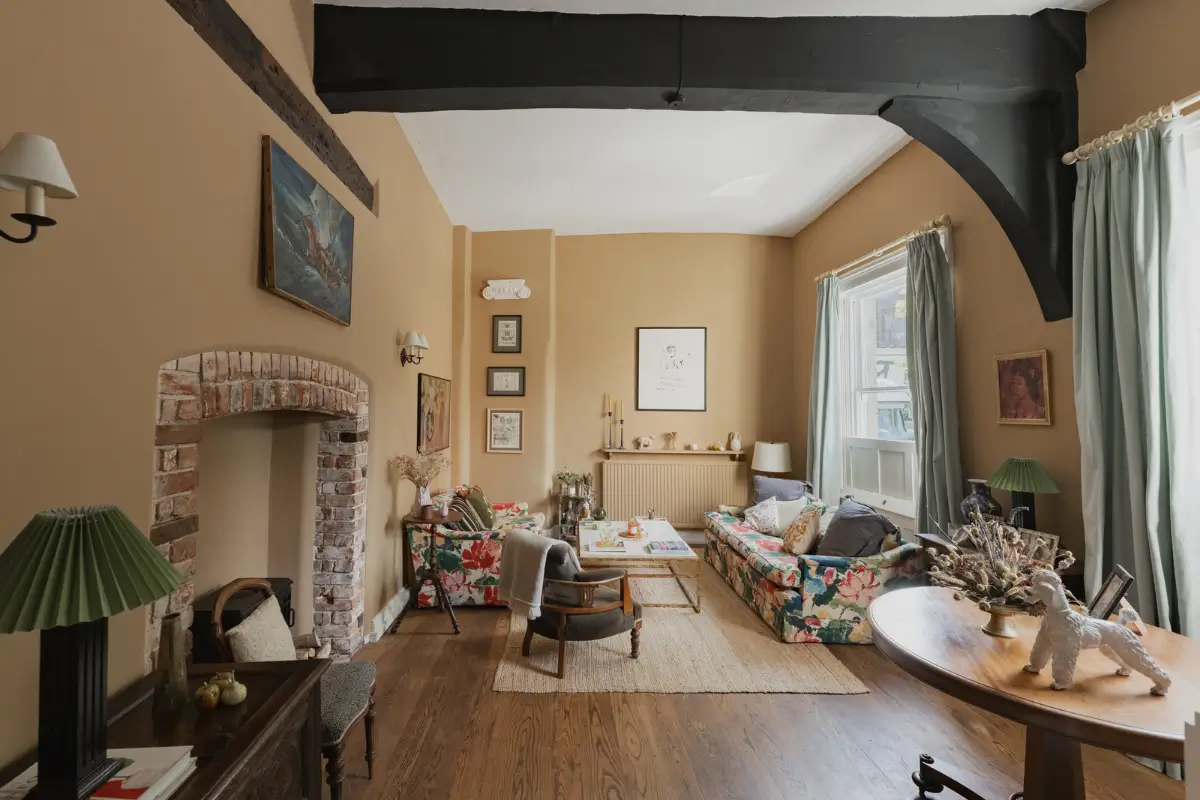 A Charming English Cottage with a Sage-Green Kitchen 1 cottage living room beige-yellow walls brick fireplace floral sofas nordroom