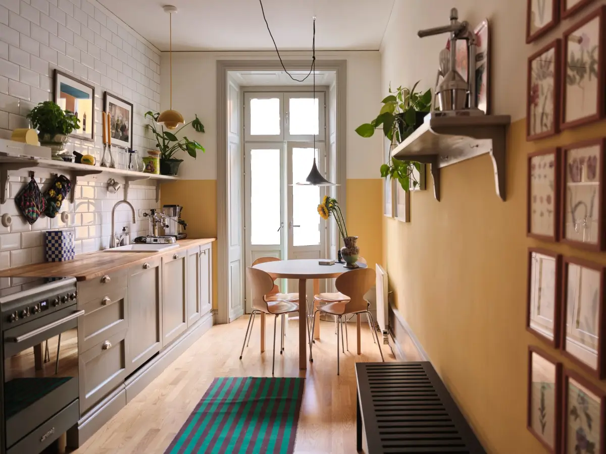 Color, Books, and a Walk-In Wardrobe in a Small Stockholm Apartment 1 kitchen-half-painted-yellow-walls-gray-cabinets-round-table-nordroom