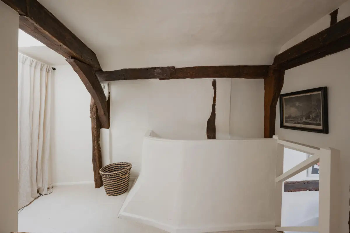 A Charming English Cottage with a Sage-Green Kitchen 21 landing exposed beams storage behind curtains
