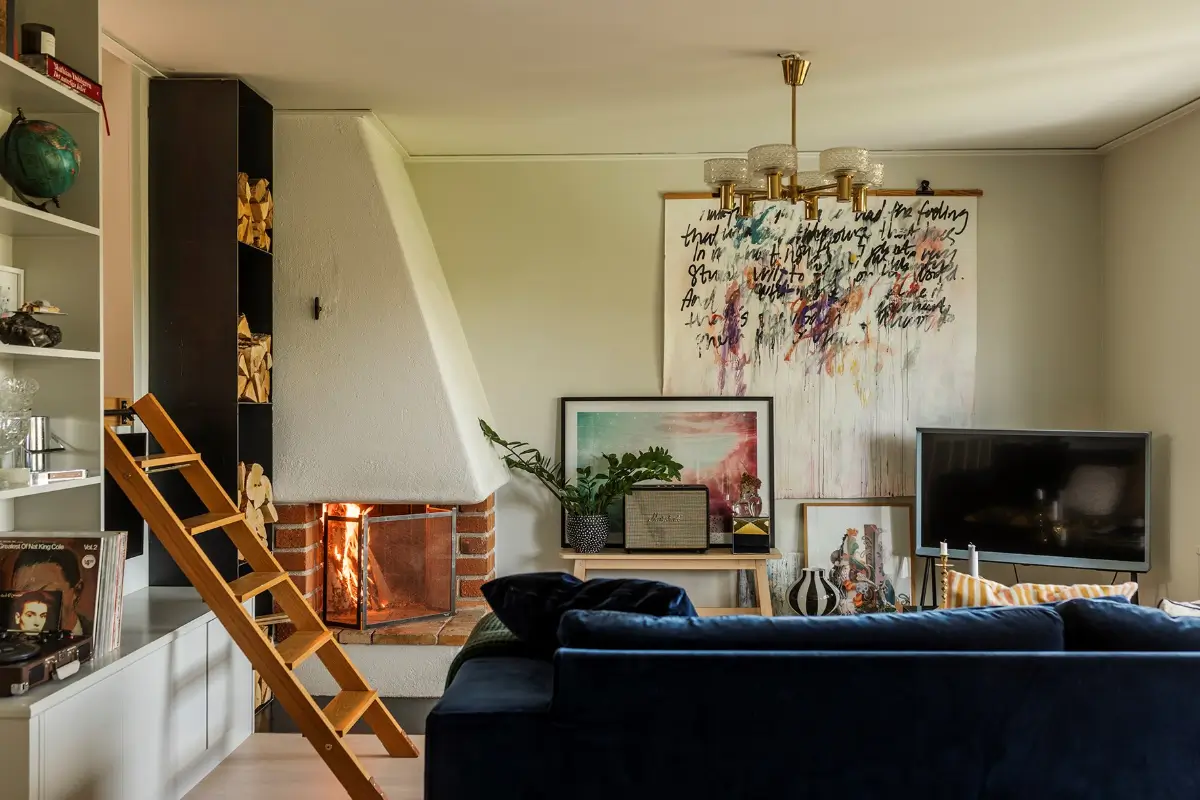A Charming 1960s Family Home in Stockholm 11 living room built-in cabinets fireplace large art blue sofa