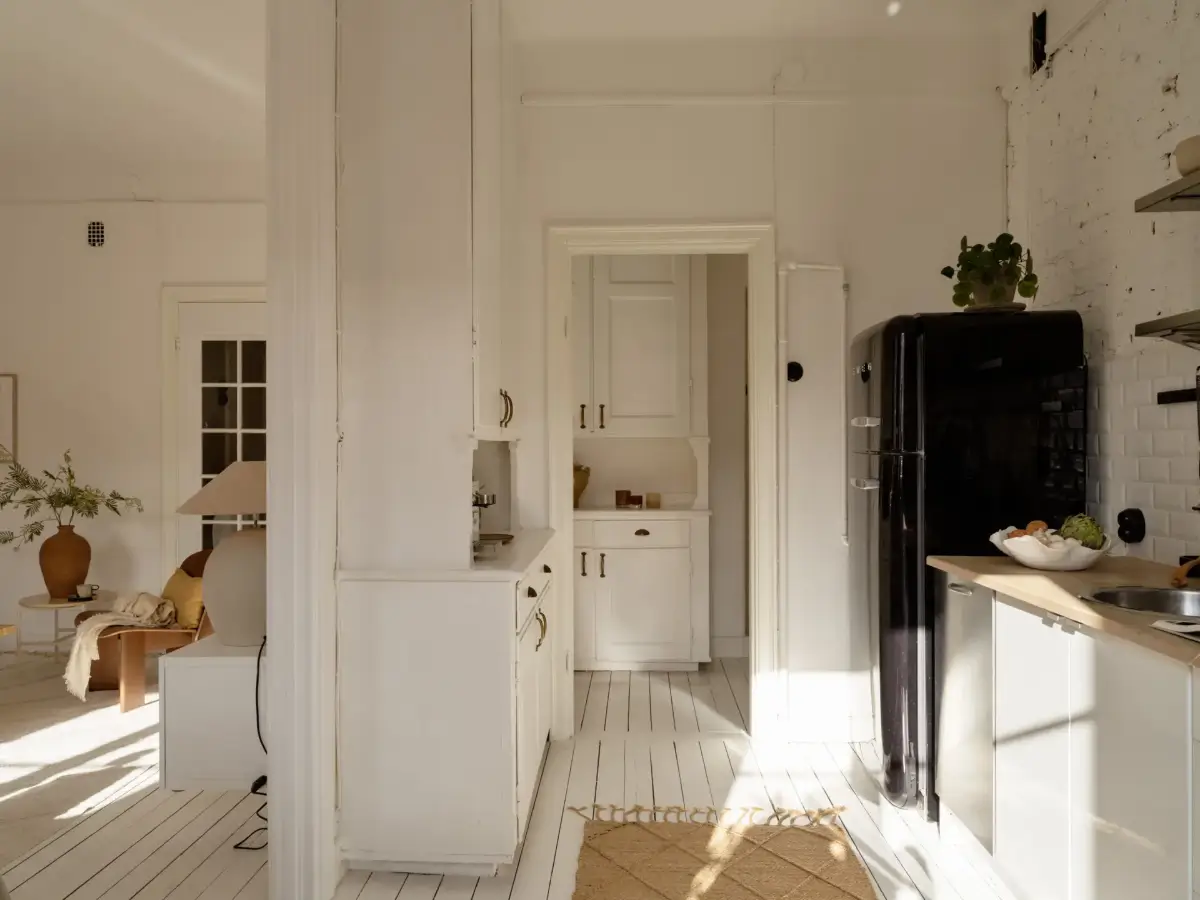 A Fresh 1920s Apartment with White Floorboards and Exposed Brick 12 white kitchen black fridge