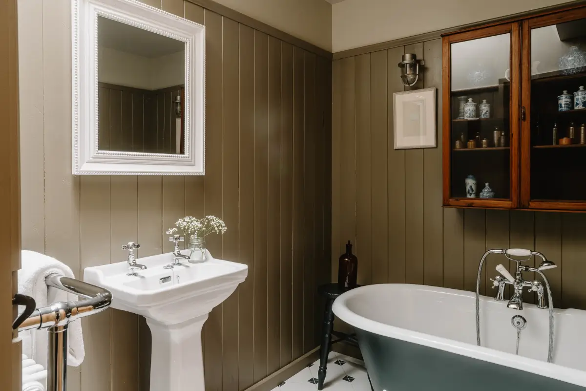 Natural Materials and Green Tones in a Pretty Coastal Home 20 bathroom green paneling glass cabinets