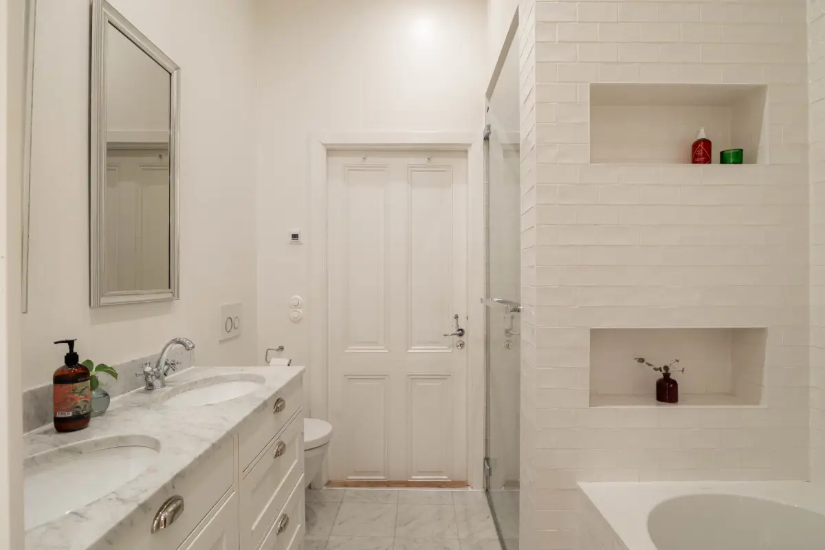 Classic Elements and Modern Comforts in an Elegant Apartment 12 classic white-tiled bathroom with shower and bath double sink
